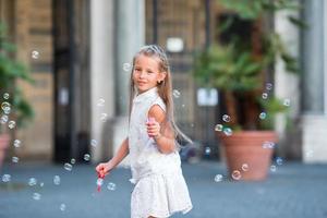 Adorable little girl blowing soap bubbles in Trastevere in Rome, Italy photo