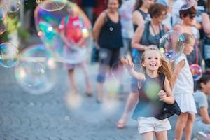 Adorable little girl blowing soap bubbles in Trastevere in Rome, Italy photo