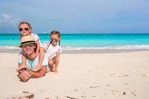 padre feliz y adorables hijitas en la playa tropical foto