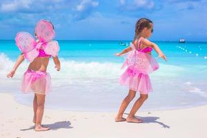 Little girls with butterfly wings have fun beach summer vacation photo