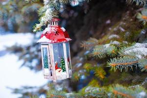 linterna de navidad decorativa en rama de abeto en la nieve día de invierno foto