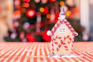 Gingerbread fairy house decorated by colorful candies on a background of bright Christmas tree with garland photo