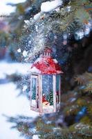 Decorative Christmas lantern on fir branch in snow winter day photo