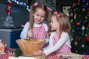 Little cute sisters bake gingerbread cookies for Christmas photo