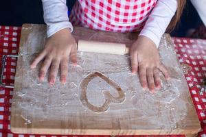 Heart drawn in flour on the board and kid's hands photo