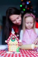 Gingerbread fairy house decorated by colorful candies on a background of happy family photo