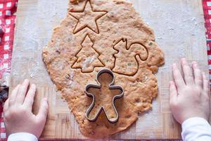 Child hands making from dough gingerbread man for Christmas photo