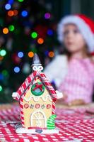 Gingerbread fairy house decorated by colorful candies on a background of little girl photo