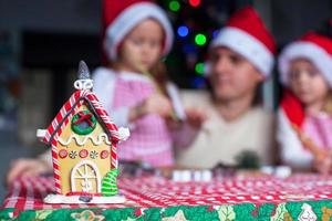 Gingerbread fairy house decorated by colorful candies on a background of happy family photo