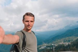 Man tourist taking selfie in mountains outdoors photo