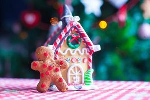 hombre de pan de jengibre frente a su fondo de casa de jengibre de caramelo las luces del árbol de navidad foto