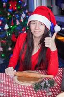 Young woman in Christmas hat raised thumbs up at home photo