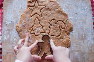 Child hands making from dough gingerbread man photo