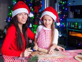 Happy mom and little girl baking Christmas gingerbread cookies together photo