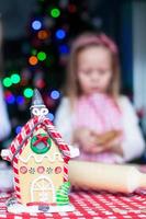 Gingerbread fairy house decorated by colorful candies on a background of little girl photo