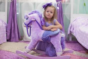 adorable niña con un caballo de juguete en casa foto