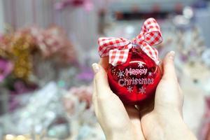 Beautiful red ball in hands of young woman for Christmas photo