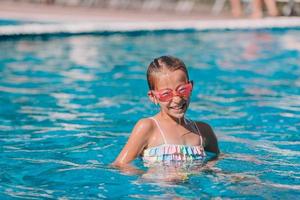 Beautiful little girl having fun near an outdoor pool photo