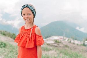 Beautiful happy little girl in mountains in the background of fog photo