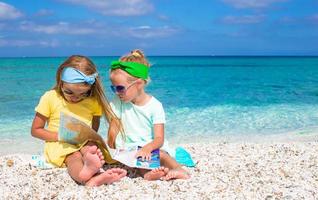 Little adorable girls with big map on tropical beach vacation photo