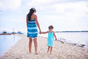 Niña y joven madre en playa tropical foto