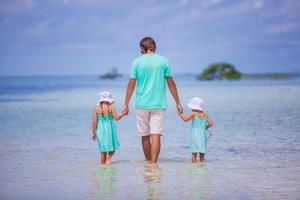 Adorable little girls and young father during beach vacation photo