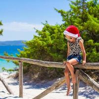 Adorable little baby girl in christmas hat during summer vacation photo