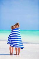 Adorable little girls wrapped in towel at tropical beach photo