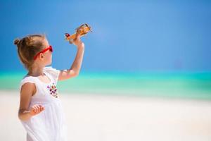 niña feliz con avión de juguete durante las vacaciones en la playa foto
