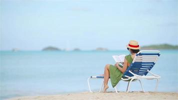 mujer joven leyendo un libro durante la playa blanca tropical video