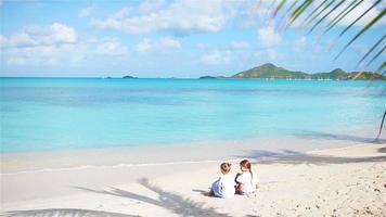 Adorable little girls playing with sand on the beach. Kids sitting on the seashore and making a sandcastle video