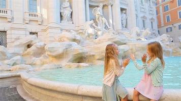 adorables petites filles près de la fontaine de trevi à rome. des enfants heureux profitent de leurs vacances européennes en italie