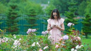 jong meisje in een bloem tuin tussen mooi rozen. geur van rozen video