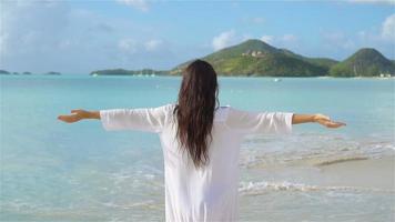 mujer hermosa joven en la costa tropical. chica feliz de fondo el cielo azul y el agua turquesa en el mar en la isla caribeña. video