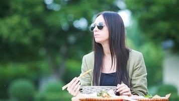 mujer joven comiendo fideos para llevar en la calle video