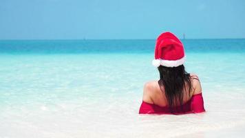 mujer con sombrero de santa en bikini en la playa tropical. camara lenta. video