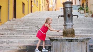 poco adorabile ragazza potabile acqua a partire dal il rubinetto al di fuori a caldo estate giorno nel Roma, Italia video