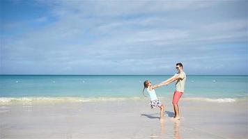 contento padre e il suo adorabile poco figlia a bianca sabbioso spiaggia avere divertimento. famiglia godere vacanza su caraibico costa video