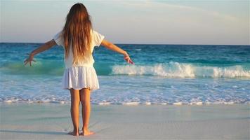 adorabile contento poco ragazza su bianca spiaggia a tramonto video