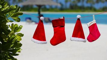 chapéus de papai noel vermelhos e meia de natal pendurado na praia tropical video
