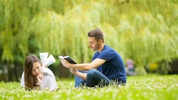 Relaxed young couple reading books while lying on grass video