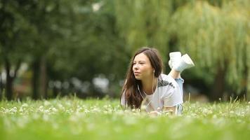 jolie femme lit un message texte sur son téléphone portable alors qu'elle est assise dans le parc. video