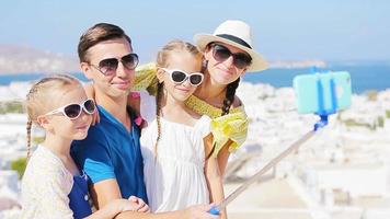 familj semester i Europa. föräldrar och barn tar selfie Foto bakgrund mykonos stad i grekland video