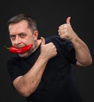 elderly man with red pepper in his mouth photo