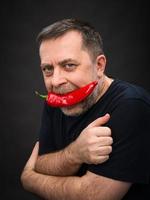 elderly man with red pepper in his mouth photo