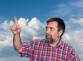 middle-aged men pointing his forefinger towards a blue sky photo