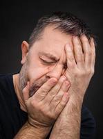 Headache. Man with face closed by hand photo