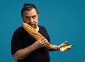 Man holds vegetables in one hand and bread in other photo