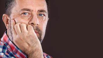 thoughtful elderly man with hand near the face photo