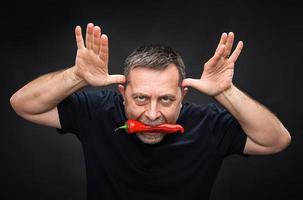 elderly man with red pepper in his mouth photo